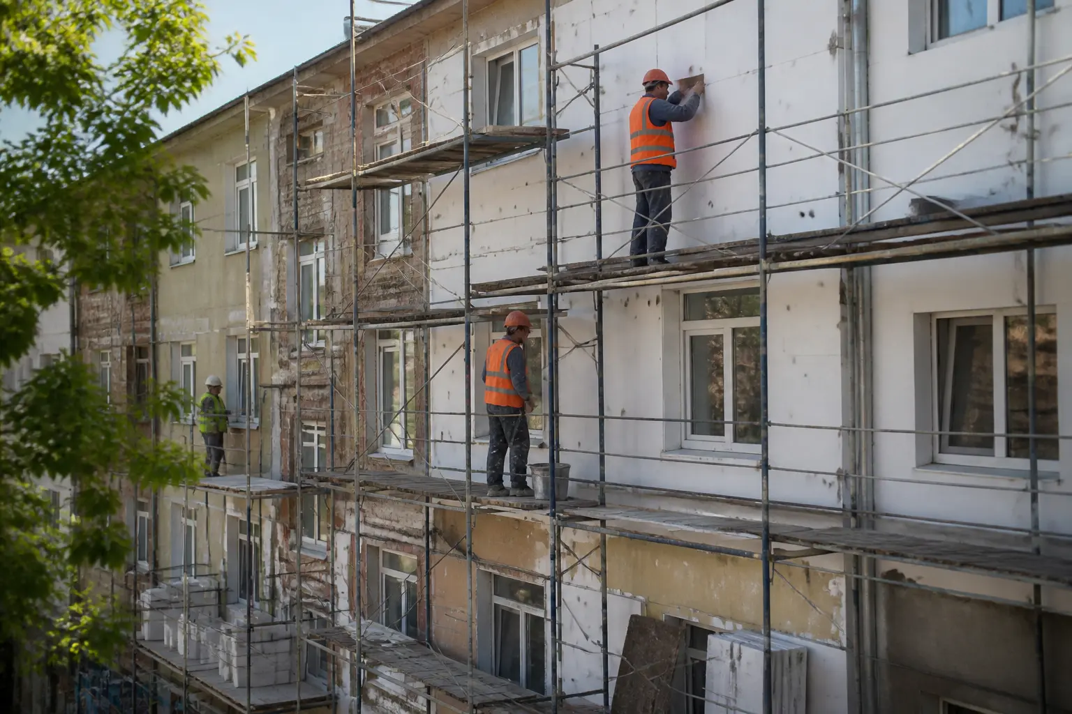 Робітники відновлюють фасад житлового будинку в Харкові