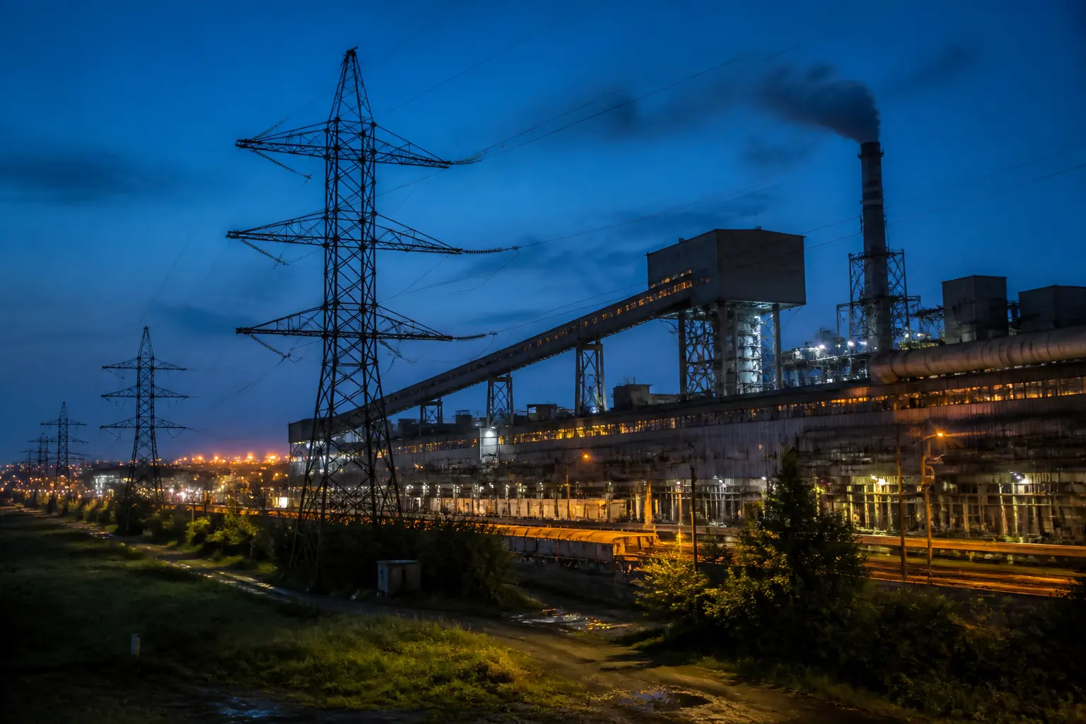 Промисловий завод з лініями електропередач увечері