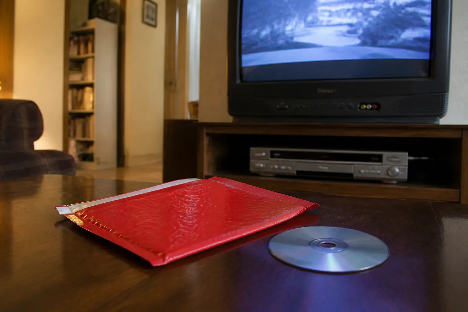 Красный почтовый конверт с DVD-диском возле телевизора — эпоха проката дисков