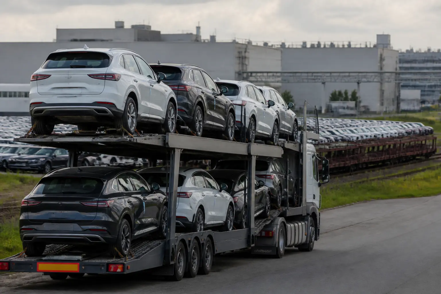 Двухуровневый автовоз с новыми автомобилями возле заводской логистической площадки