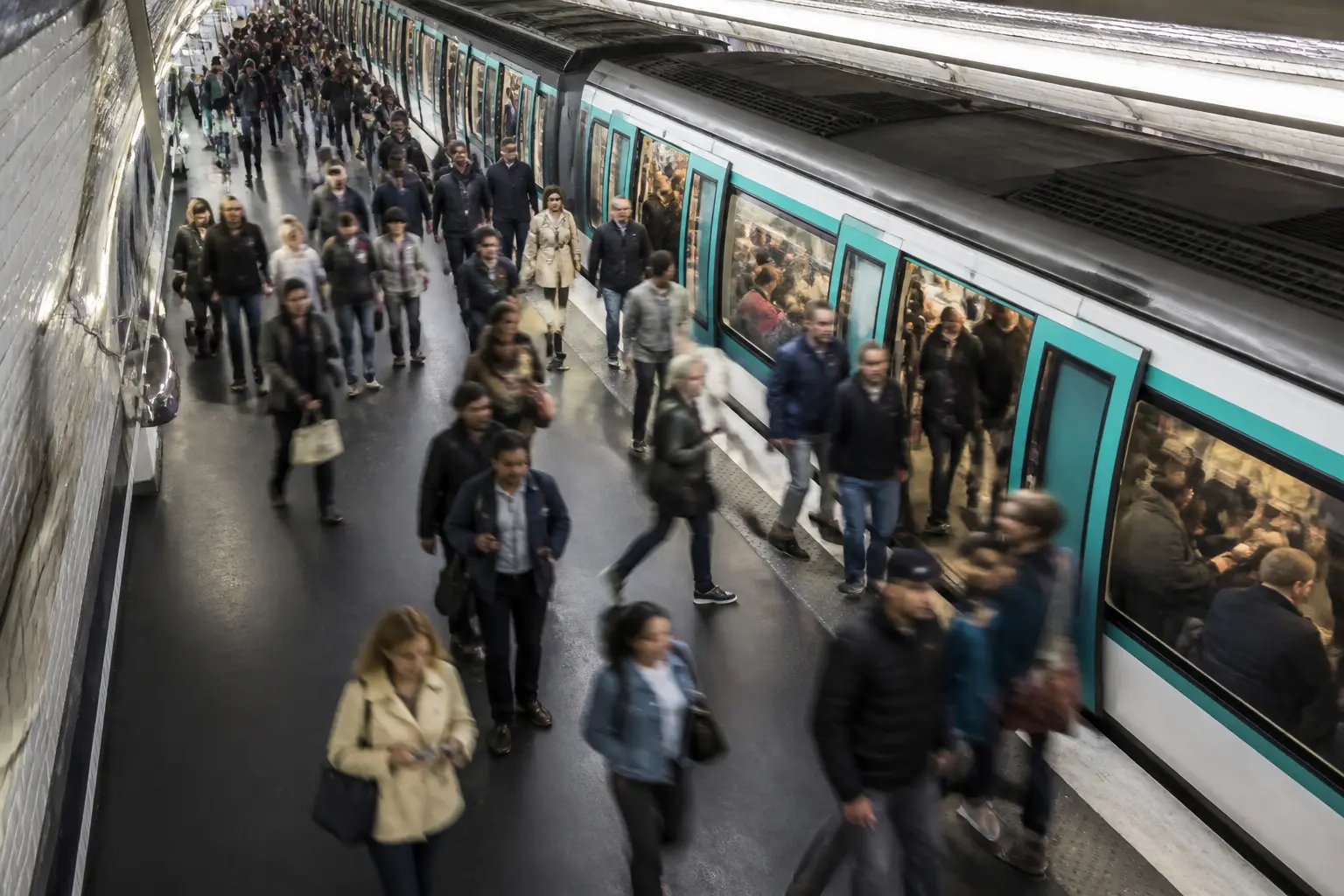 Платформа паризького метро з пасажирами, що заходять у потяг